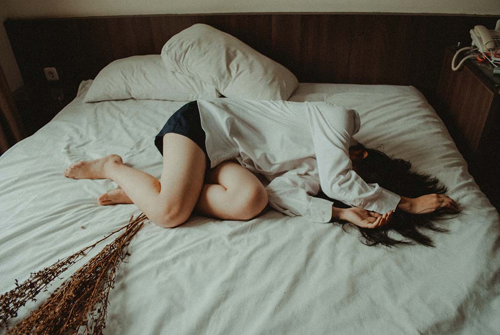 Mulher exausta deitada na cama